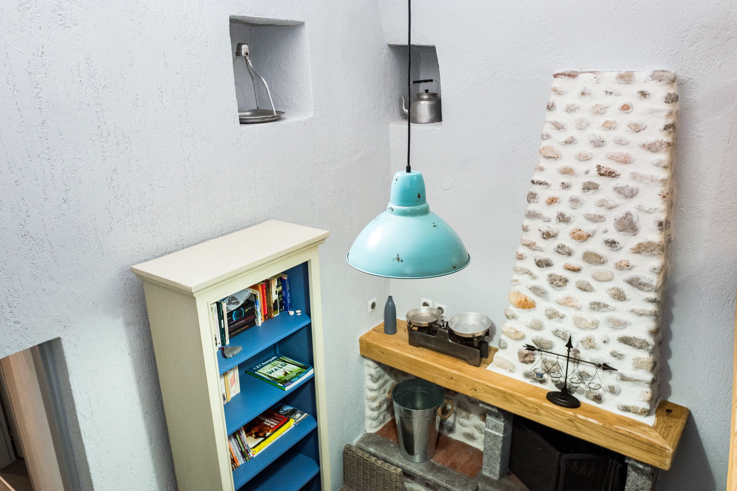 A room with a bookshelf, a hanging light, and a decorative wall piece.