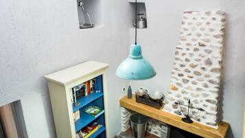 A room with a bookshelf, a hanging light, and a decorative wall piece.
