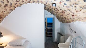 A bedroom with a bed, a chair, a desk, and a ladder leading to a lofted sleeping area.