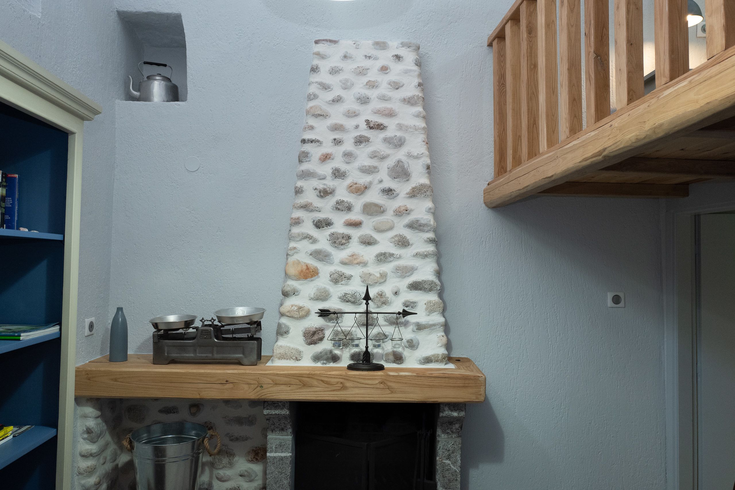 A kitchen with a stone backsplash, wooden shelves, and a gas stove.