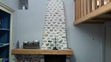 A kitchen with a stone backsplash, wooden shelves, and a gas stove.