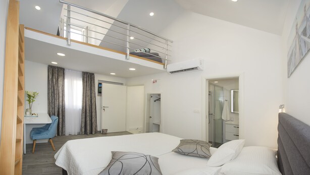 A modern hotel room with a large bed, a desk, and a balcony. - Central Old Town Rooms (Split)