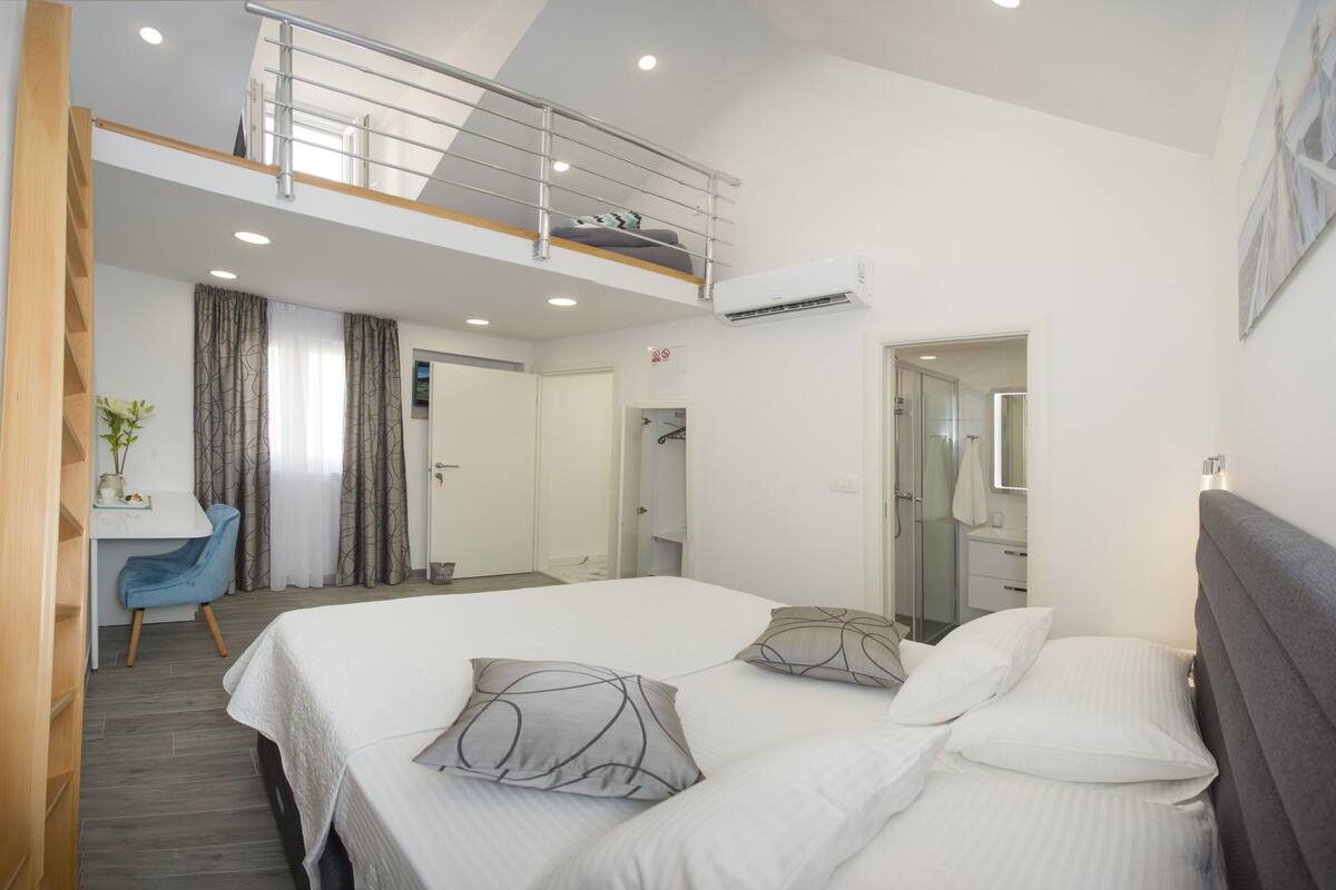 A modern hotel room with a large bed, a desk, and a balcony.