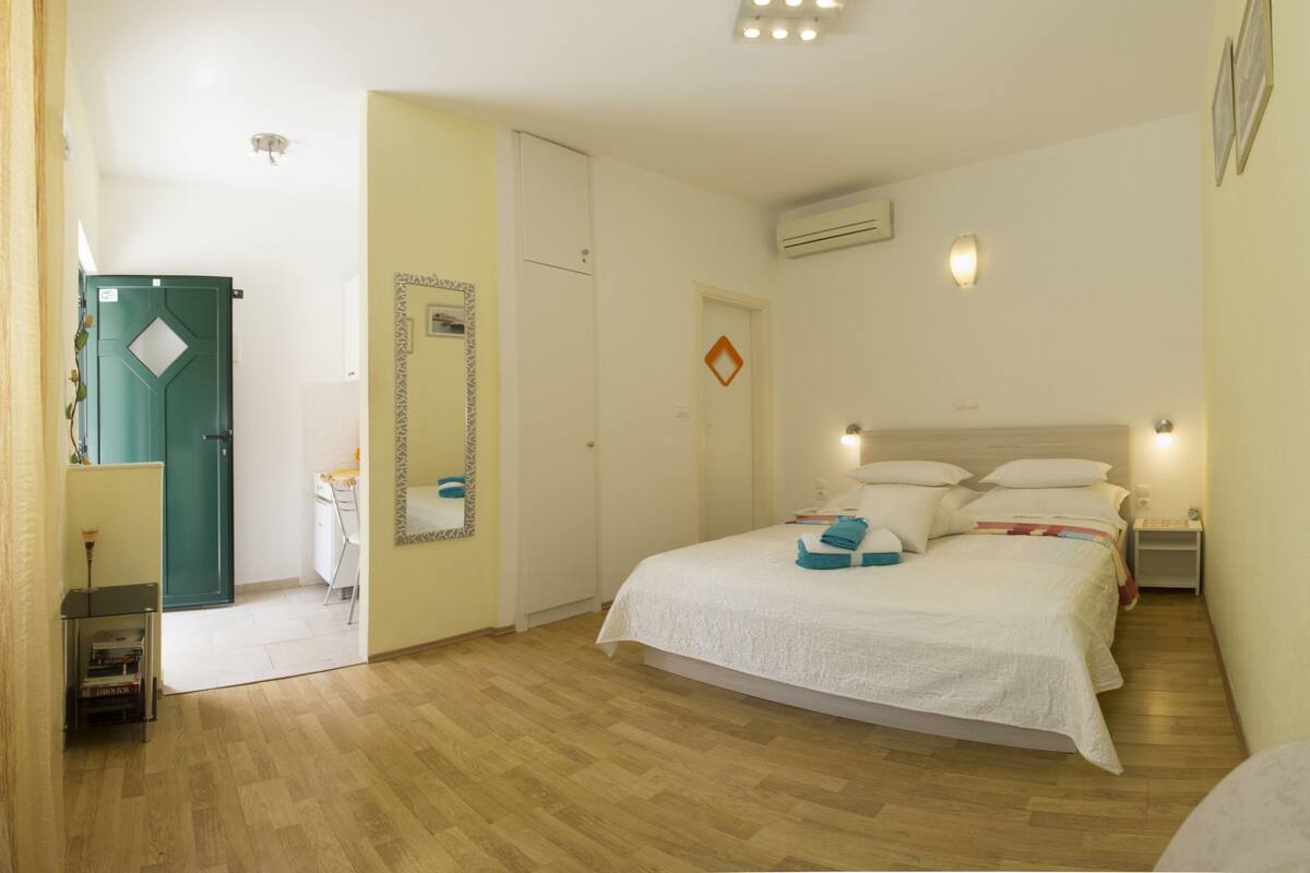 A bedroom with a bed, bedside tables, a mirror, and a door.