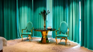 A room with teal curtains, a round table with chairs, and a vase with dried plants. - Elegance Hotel (Ulaanbaatar)