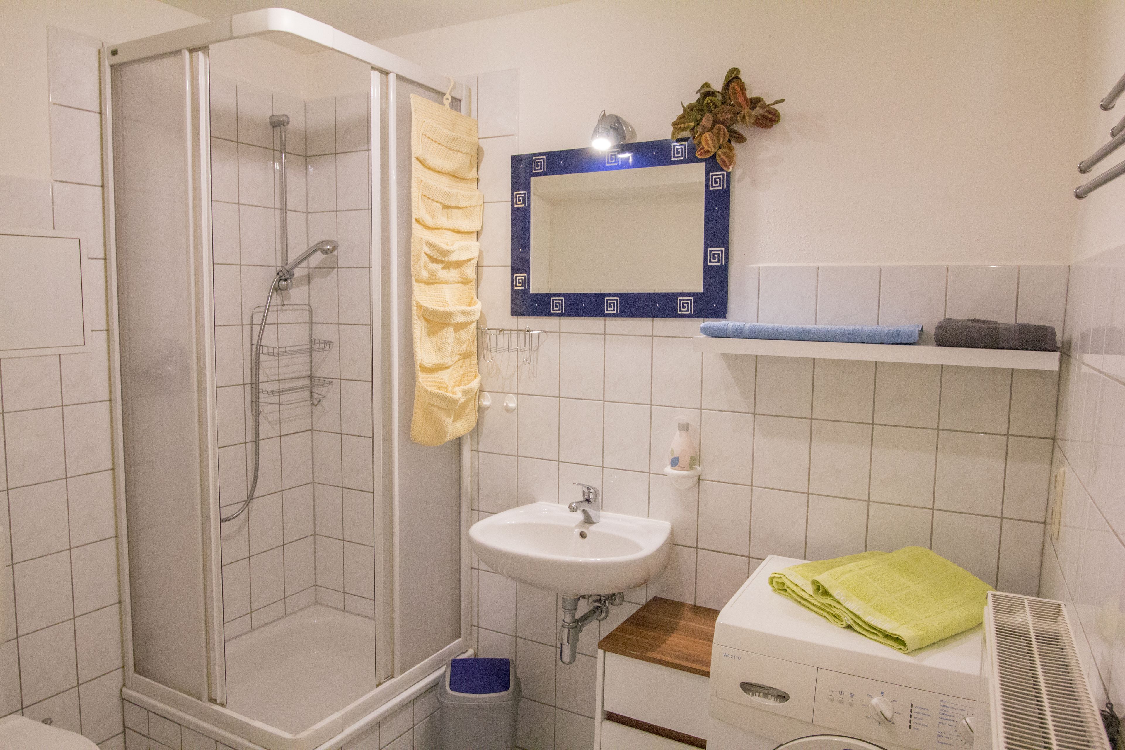 A bathroom with a shower, sink, and a mirror.