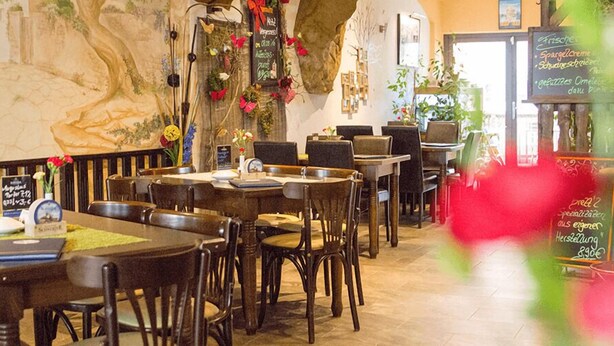 Un restaurante con mesas y sillas de madera, un menú en una pizarra y un mural en la pared.