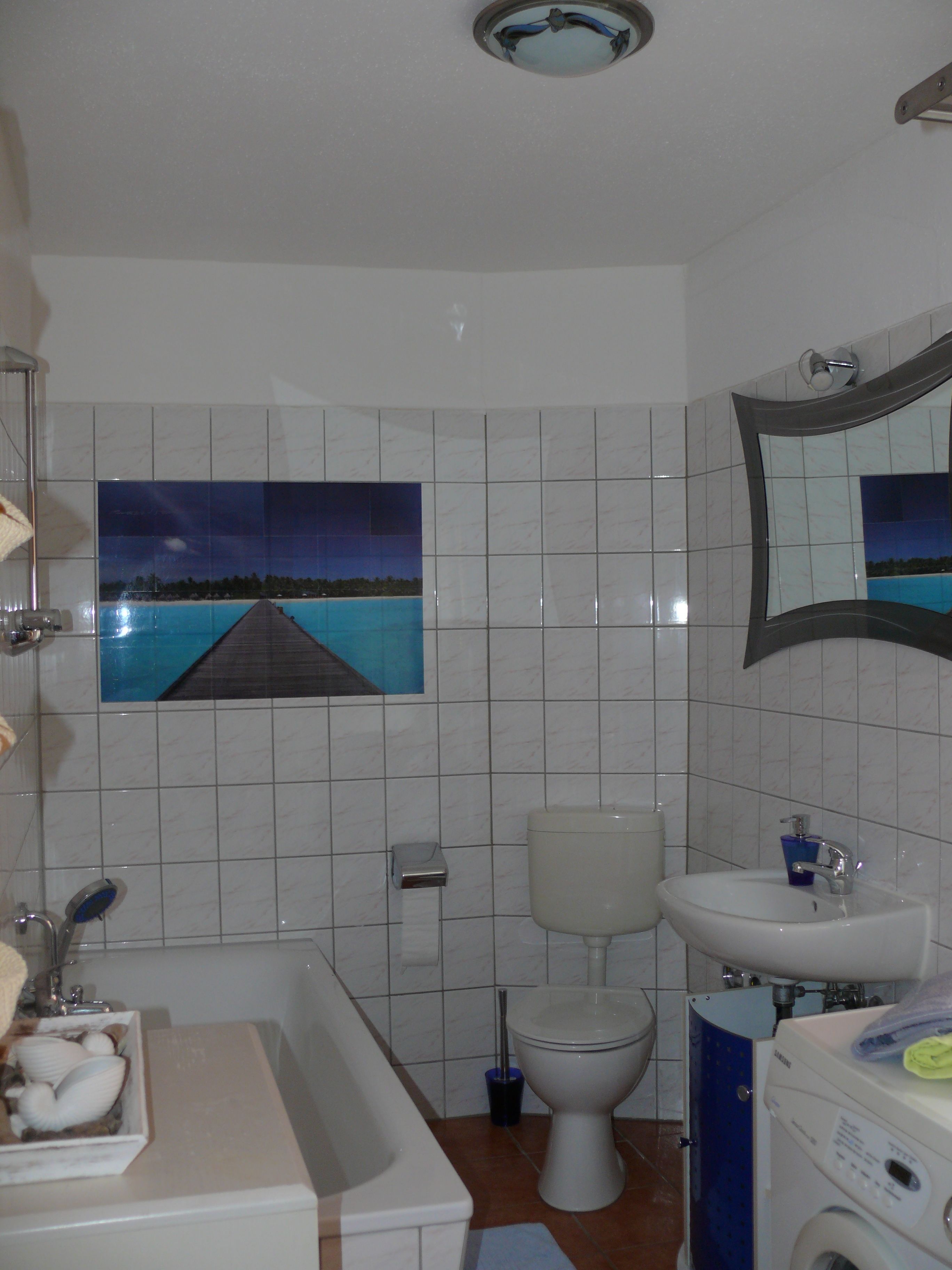 A bathroom with a bathtub, toilet, sink, and a large mirror.