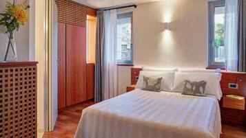 Une chambre à coucher bien aménagée, avec un grand lit, un plancher en bois, une armoire en bois et une fenêtre avec des rideaux.
