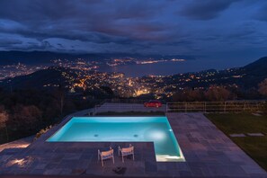 Une piscine avec deux chaises longues et une voiture rouge garée à proximité.