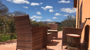 A patio with wicker furniture and a round table, overlooking a scenic landscape. - Agriturismo L'Ulivo (Padula)