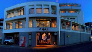 A multi-story building with a restaurant on the ground floor, featuring a large illuminated sign and a vending machine outside. - Himakajima Ocean View Hotel Seikaiso (Minamichita)