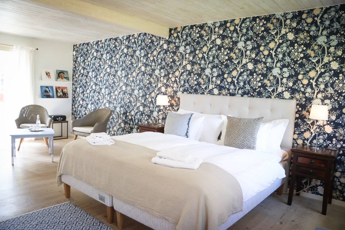 A neatly arranged bedroom with a large bed, two bedside tables, a chair, and a small table.