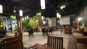 A modern indoor space with wooden furniture, a stone wall with greenery, and hanging plants. - Monarch Hotel Amman (Amman)
