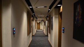 A long, narrow hotel corridor with carpeted floors, wooden doors, and framed artwork on the walls. - Monarch Hotel Amman (Amman)
