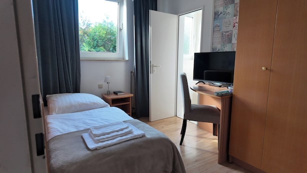 A hotel room with a bed, a desk, a chair, a TV, and a wardrobe. - Hotel Rosenhof (Bergen)