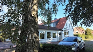 A white building with a red roof, a car parked in front, and a tree in the foreground. - Hotel Rosenhof (Bergen)