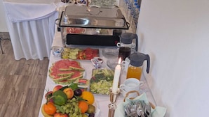 A buffet table with various food items, including fruits, vegetables, and breads, along with plates and utensils. - Hotel Rosenhof (Bergen)