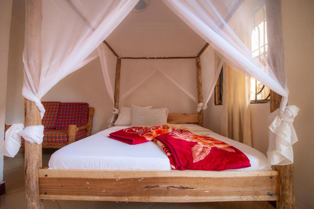 A bed with a canopy, a red plaid chair, and a wooden headboard.