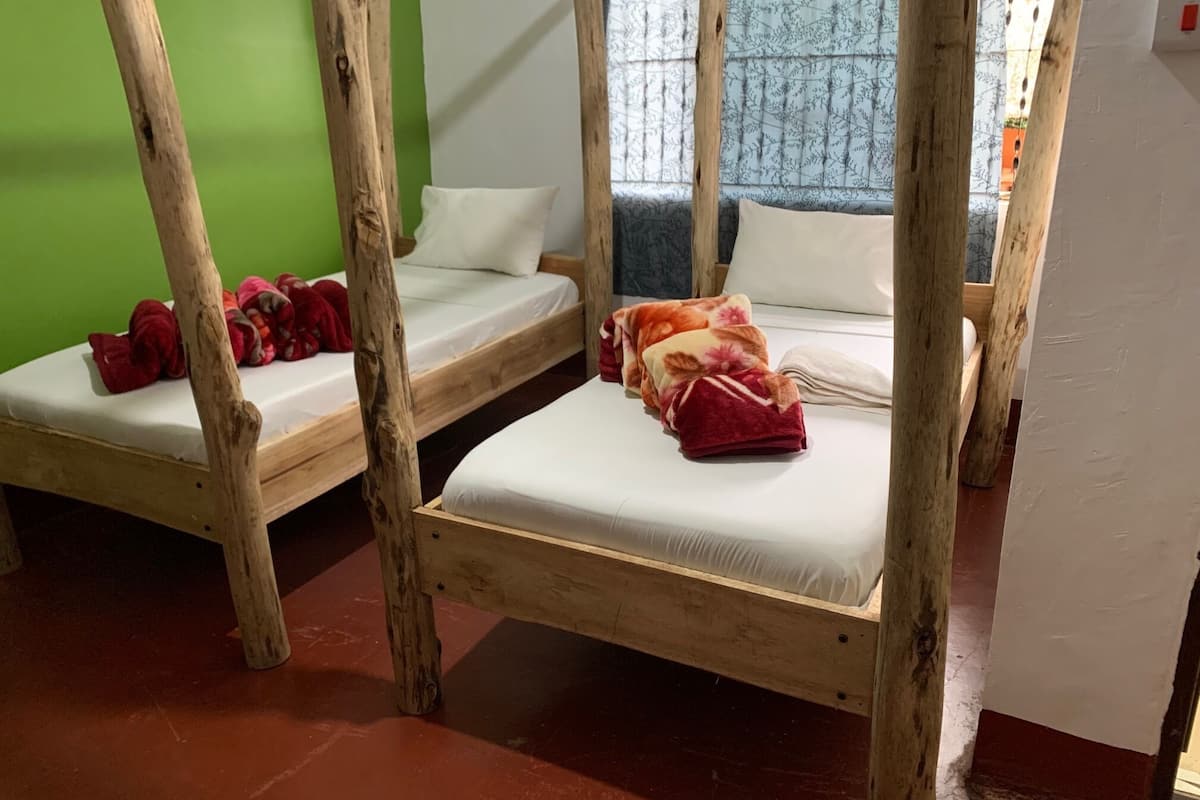 A room with two wooden bunk beds, each with a mattress and pillows.