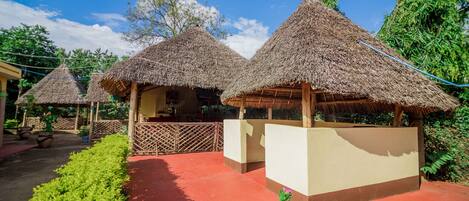 Cabañas con techo de paja, bancos de madera y un sendero rojo.
