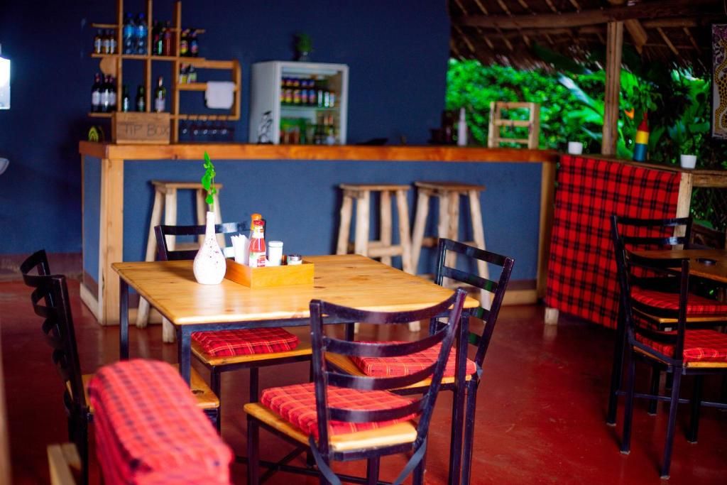 A restaurant interior with wooden tables and chairs, a bar area with shelves of bottles, and a counter.