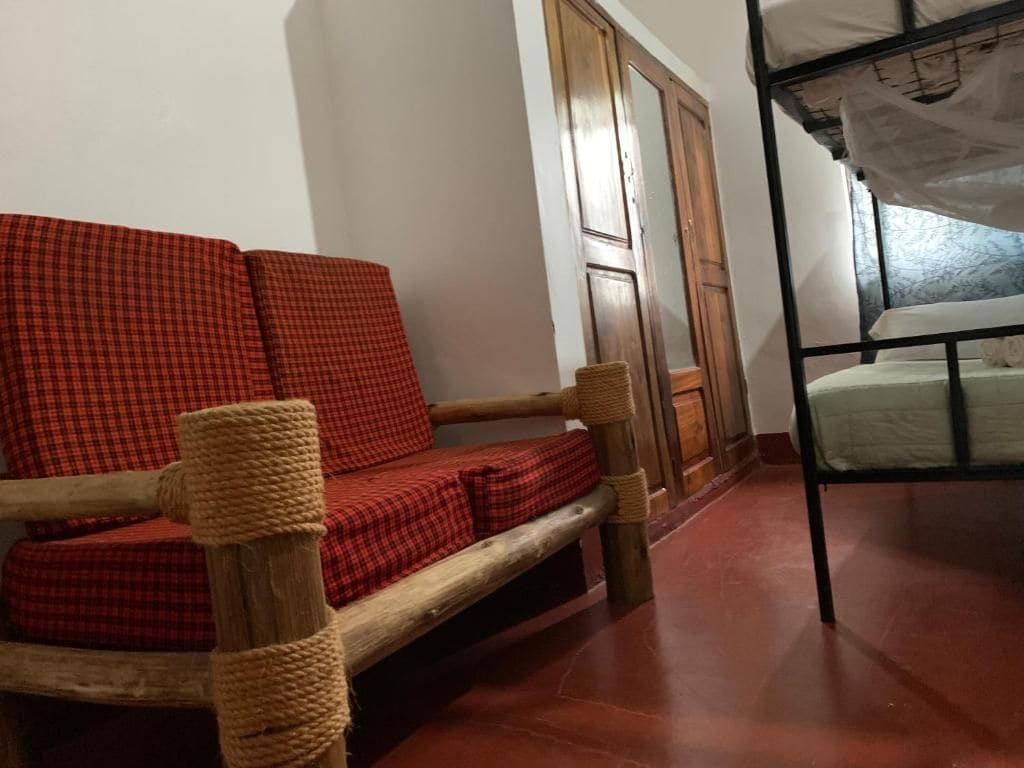 A room with a wooden bench, a bed with a mosquito net, and a wooden door.