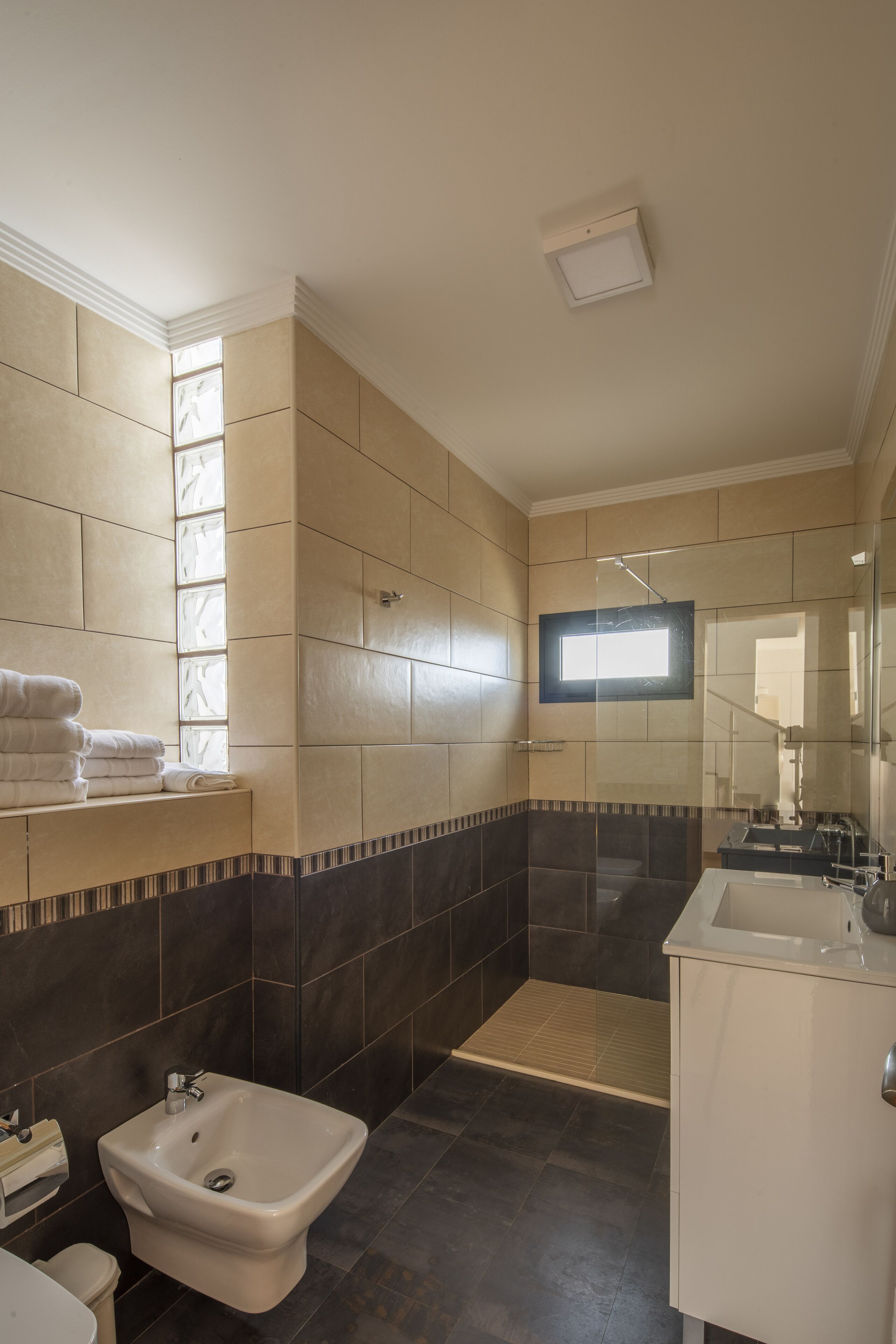 A bathroom with a bidet, a sink, and a mirror.