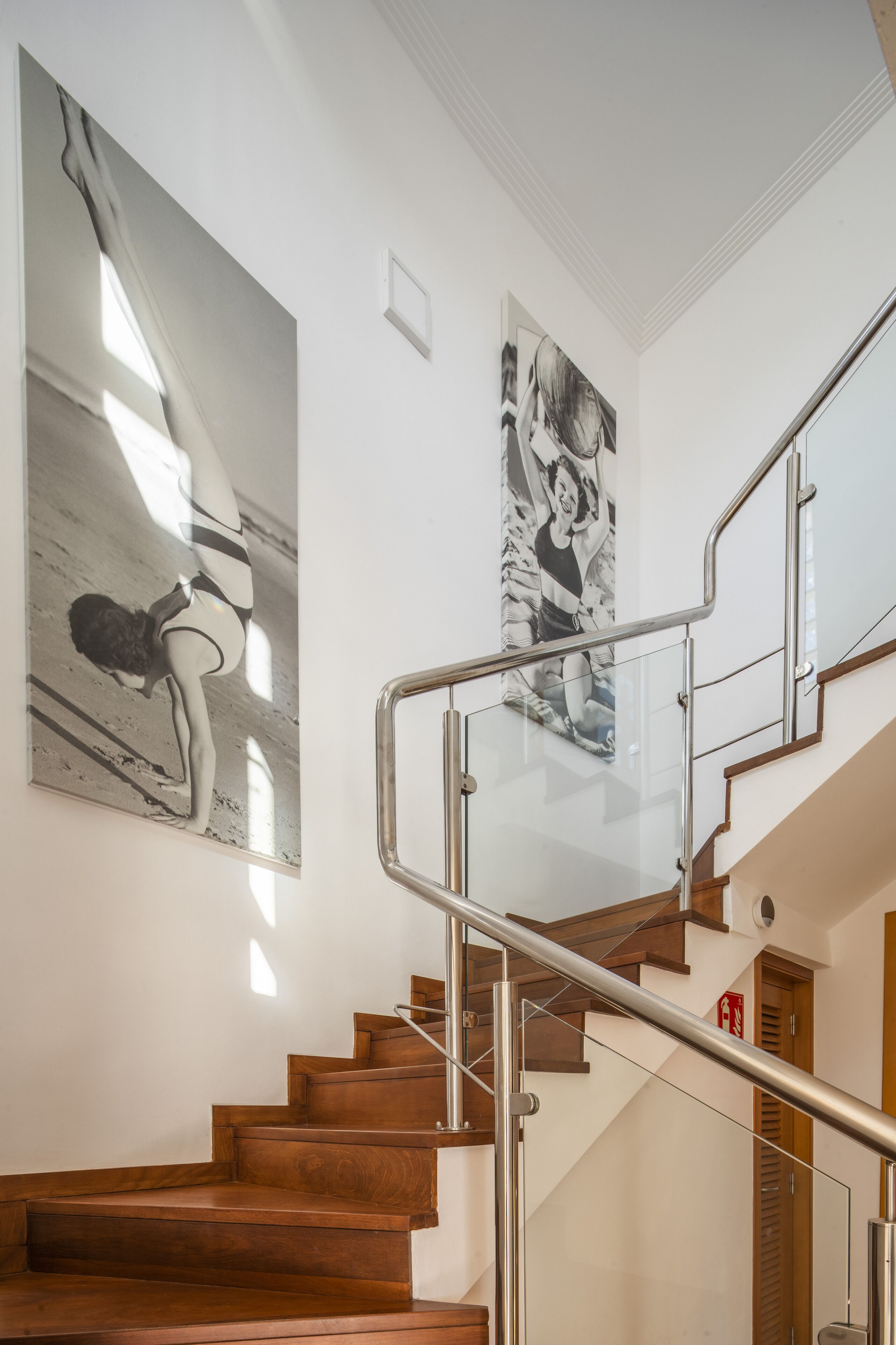 A staircase with wooden steps and a glass railing, leading to an upper floor.