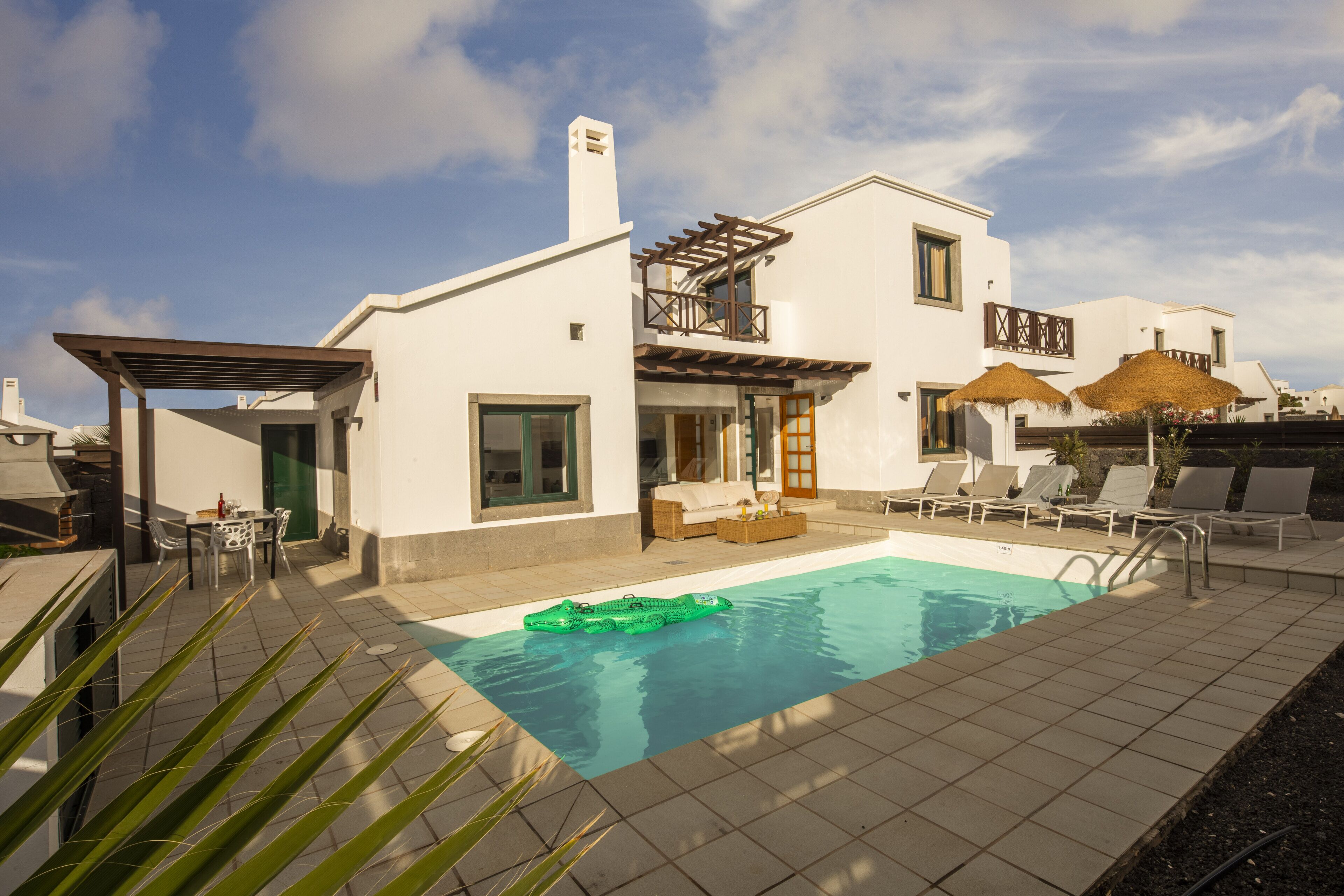A modern house with a swimming pool, outdoor seating, and a pergola.