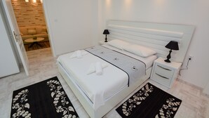 Ein modernes Schlafzimmer mit einem großen Bett, Nachttischen und einer kleinen Sitzecke mit Sofa und Tisch.