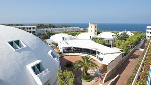 A resort with white domed buildings, a palm tree, and a view of the sea. - Cala Corvino Hotel Resort (Monopoli)