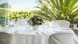 A table set for dining with a floral centerpiece, surrounded by chairs and dining utensils. - Cala Corvino Hotel Resort (Monopoli)