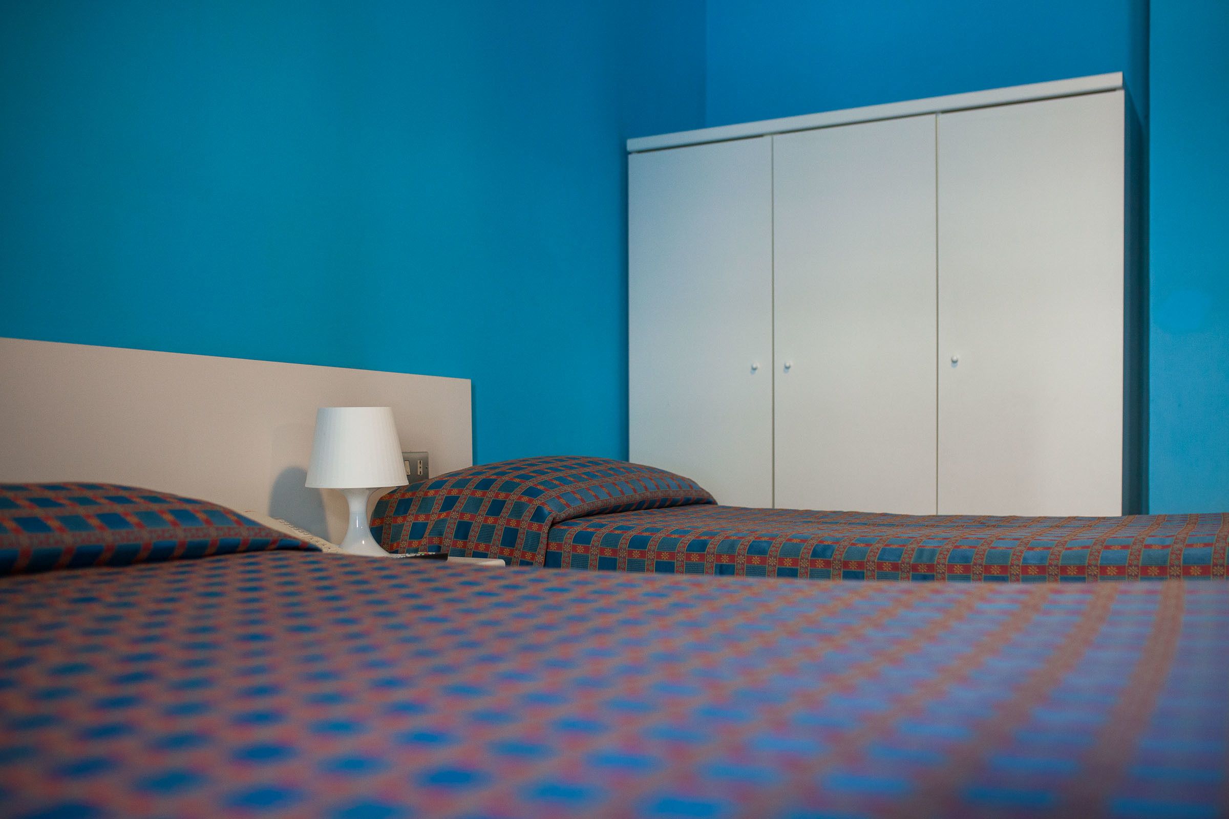 A room with a bed, a nightstand, a lamp, and a wardrobe.
