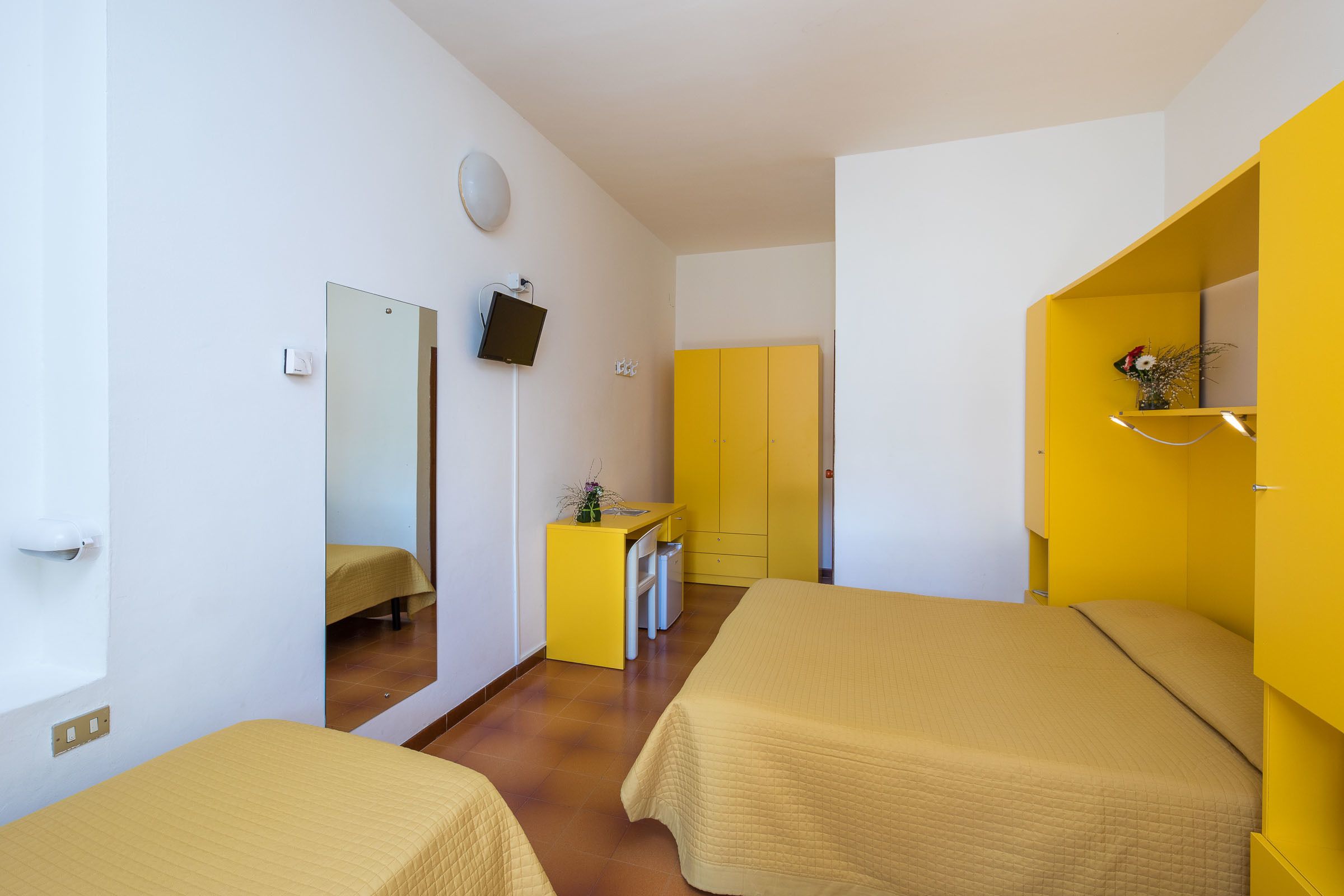 Een hotelkamer met twee bedden, een bureau, een spiegel en een kledingkast.