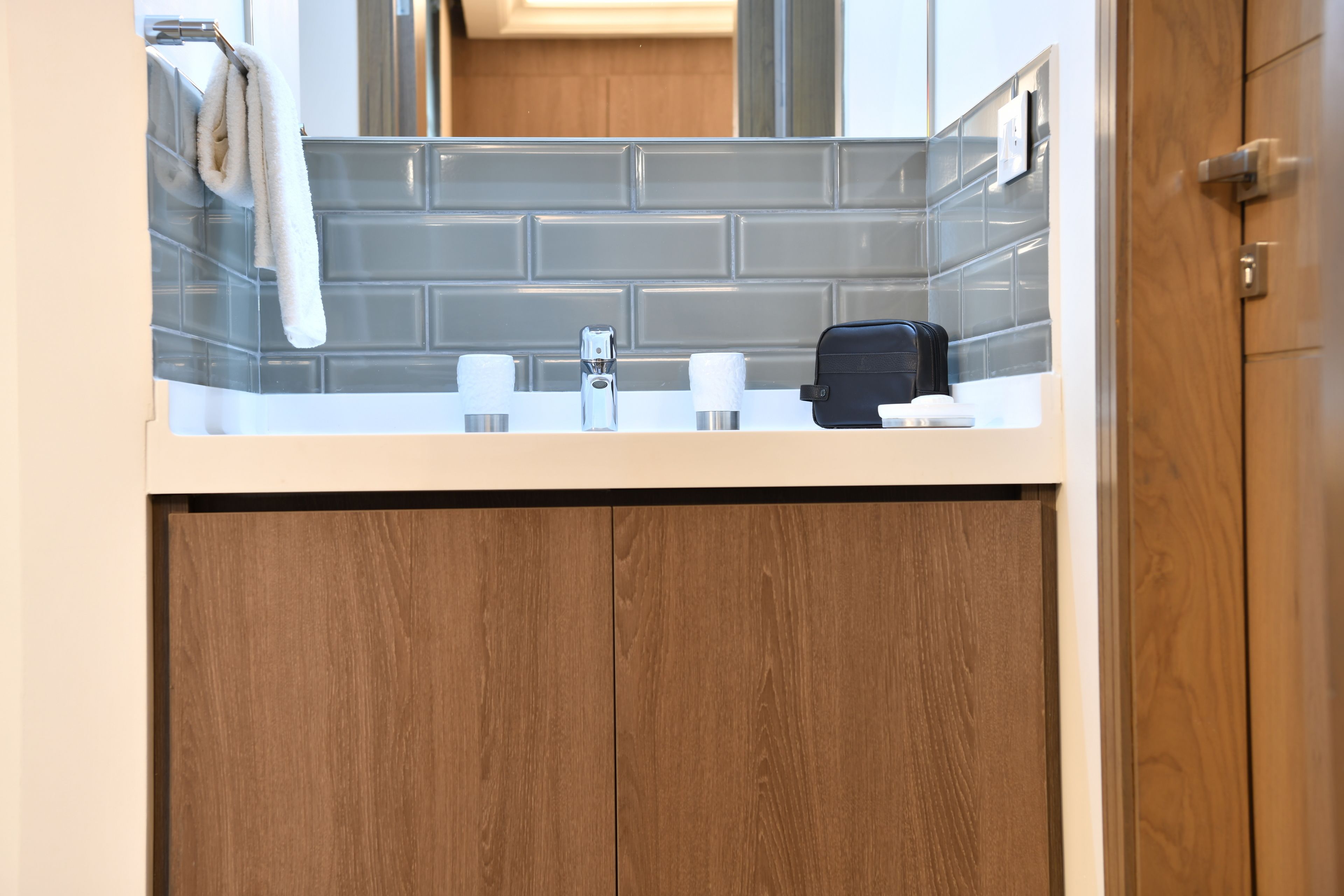 A bathroom with a tiled backsplash, a sink, a mirror, and a wooden cabinet below.