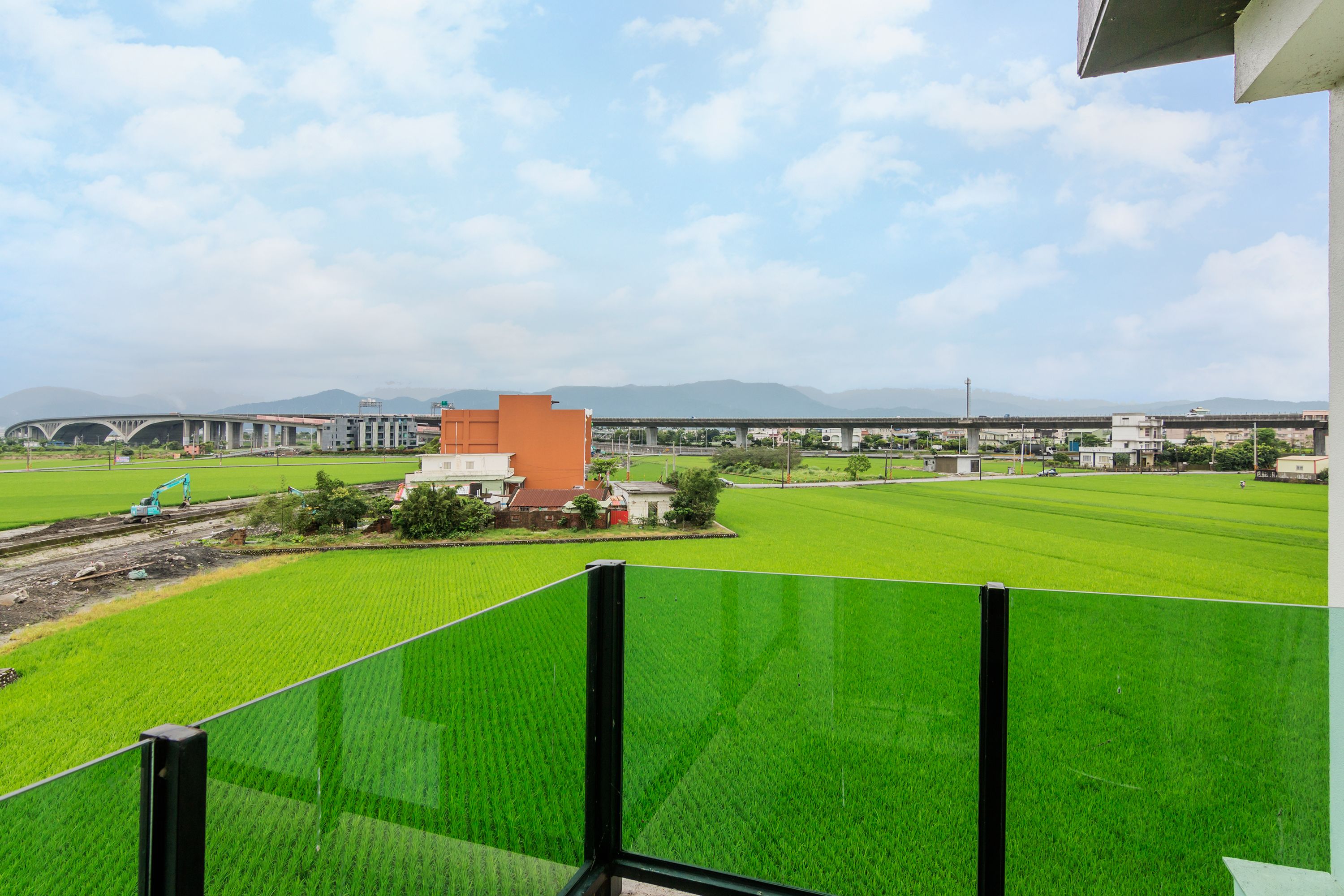 Une vue d’un champ verdoyant, avec un chantier de construction et des bâtiments en arrière-plan.
