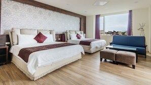 A hotel room with two beds, a sofa, a coffee table, and a view of the city. - Kano Resort (Luodong)