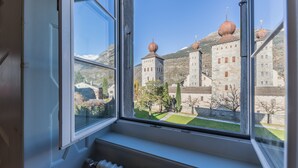 A view from a window overlooking a historic building with stone architecture and domed roofs. - Gästehaus St. Ursula (Brig)
