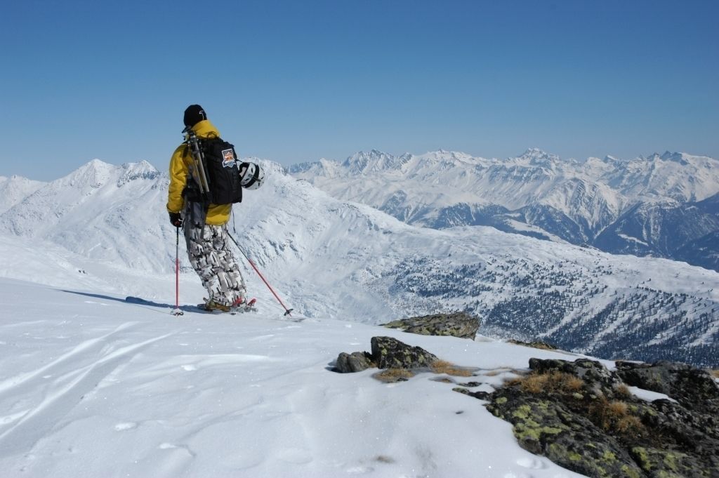 A person on a snowy mountain with a clear view of distant mountains.