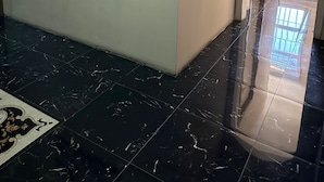 A hallway with a black and white photograph on the wall, a tiled floor, and a door leading to another room. - Adana Akdeniz Otel (Adana)