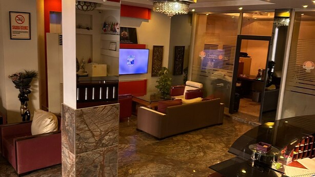 A modern living room with a marble floor, a sofa, a TV, and a glass coffee table. - Adana Akdeniz Otel (Adana)