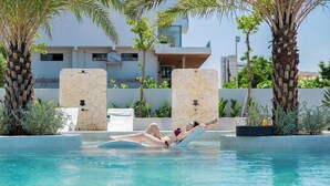 A pool area with a person lying on a lounge chair.