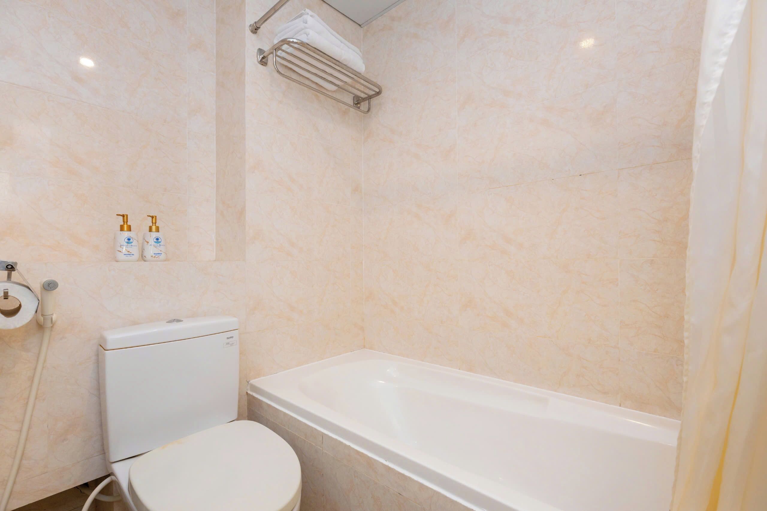 Un baño con inodoro, bañera y un perchero para toallas.