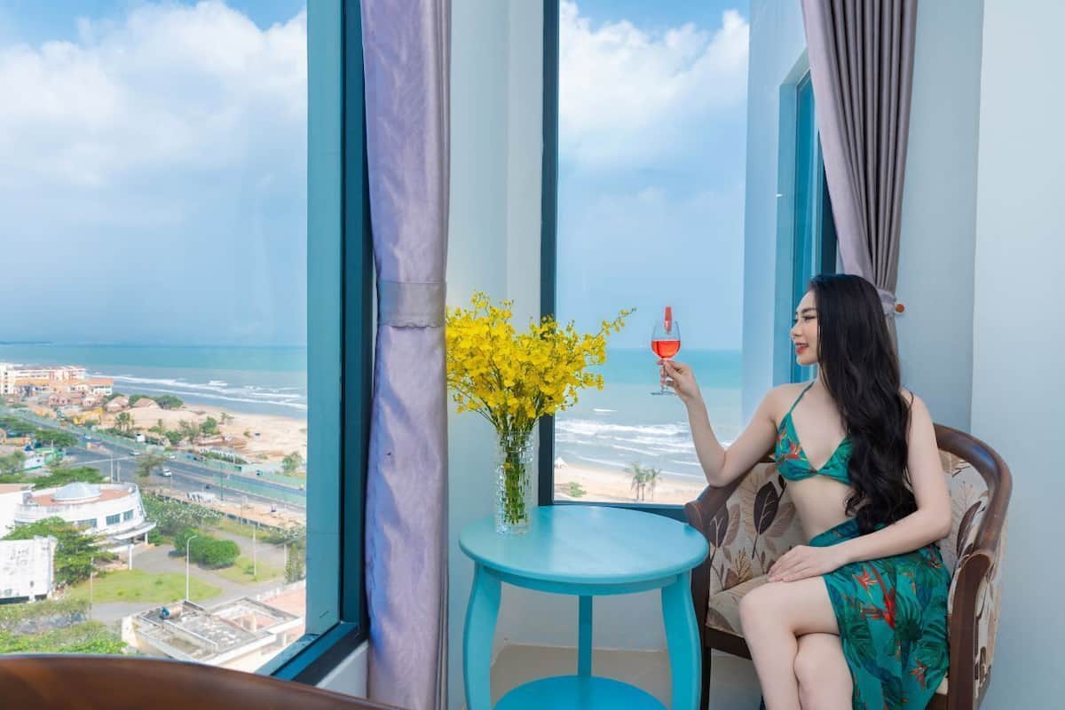 A room with a large window overlooking a beach and cityscape.