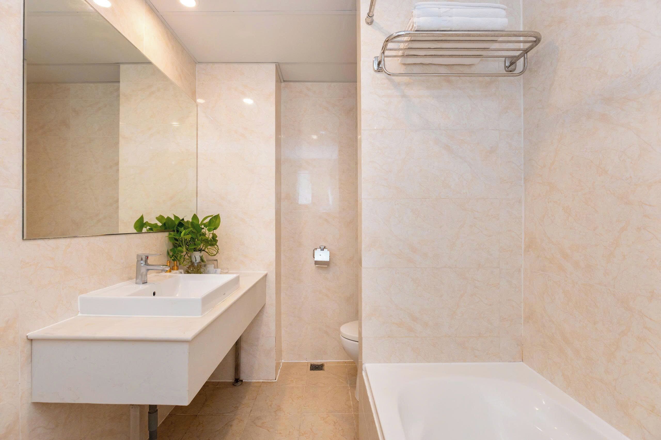 Un baño moderno con lavamanos, espejo y bañera blancos.