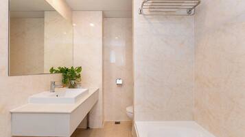 Un baño moderno con lavamanos, espejo y bañera blancos.