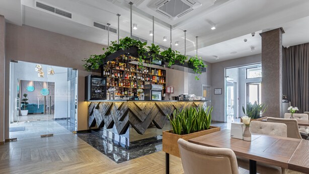 A modern hotel lobby with a bar area, wooden flooring, and a seating area with a table and chairs. - Redling Hotel (Odesa)