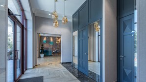 A modern hotel lobby with a marble floor, glass doors, and pendant lighting. - Redling Hotel (Odesa)