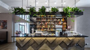 A bar area with a wooden counter, shelves of liquor bottles, and hanging plants. - Redling Hotel (Odesa)